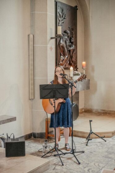 Hannah steht in der Kirche und singt beim Soundcheck Lieder für eine kirchliche Trauung.