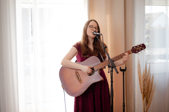 Hochzeitssängerin Hannah Stienen steht vor einem hellen Vorhang und singt.