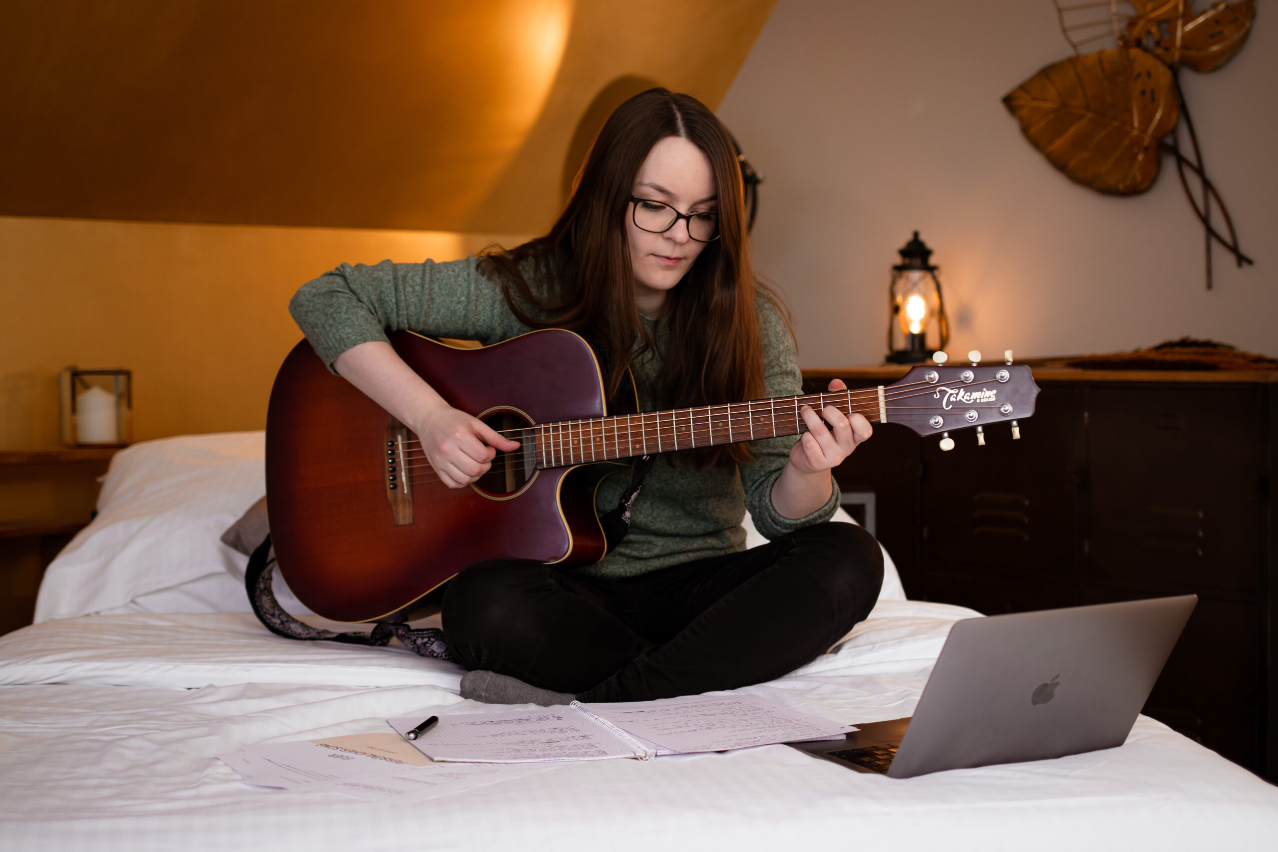 Hannah Stienen sitzt mit ihrer Gitarre auf einem Bett und schreibt den Song zum Weltfrühchentag.